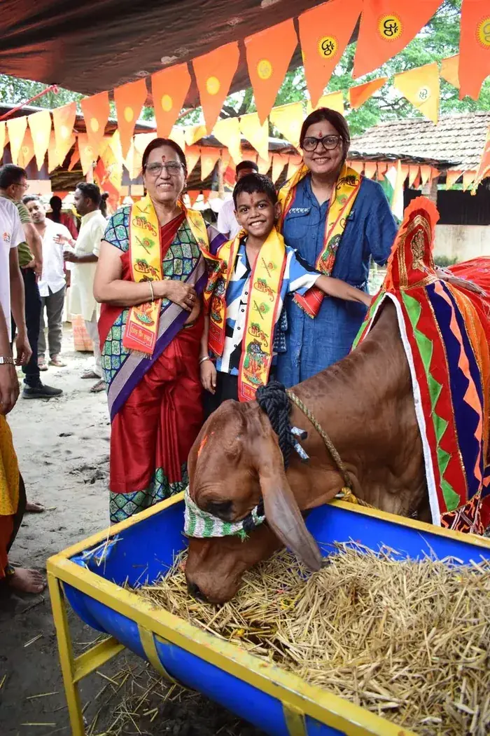 Two visitors in ceremonial shawls standing with Gau Mata